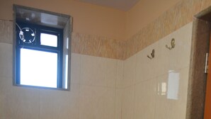 Casa de banho com sanita, janela e paredes em azulejo.