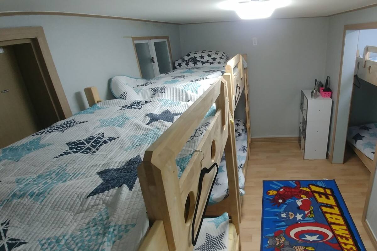 A bedroom with bunk beds, a desk, and a poster on the floor.