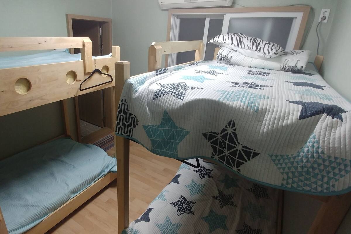 A bunk bed with a wooden frame, a mattress, and a quilt with geometric patterns.