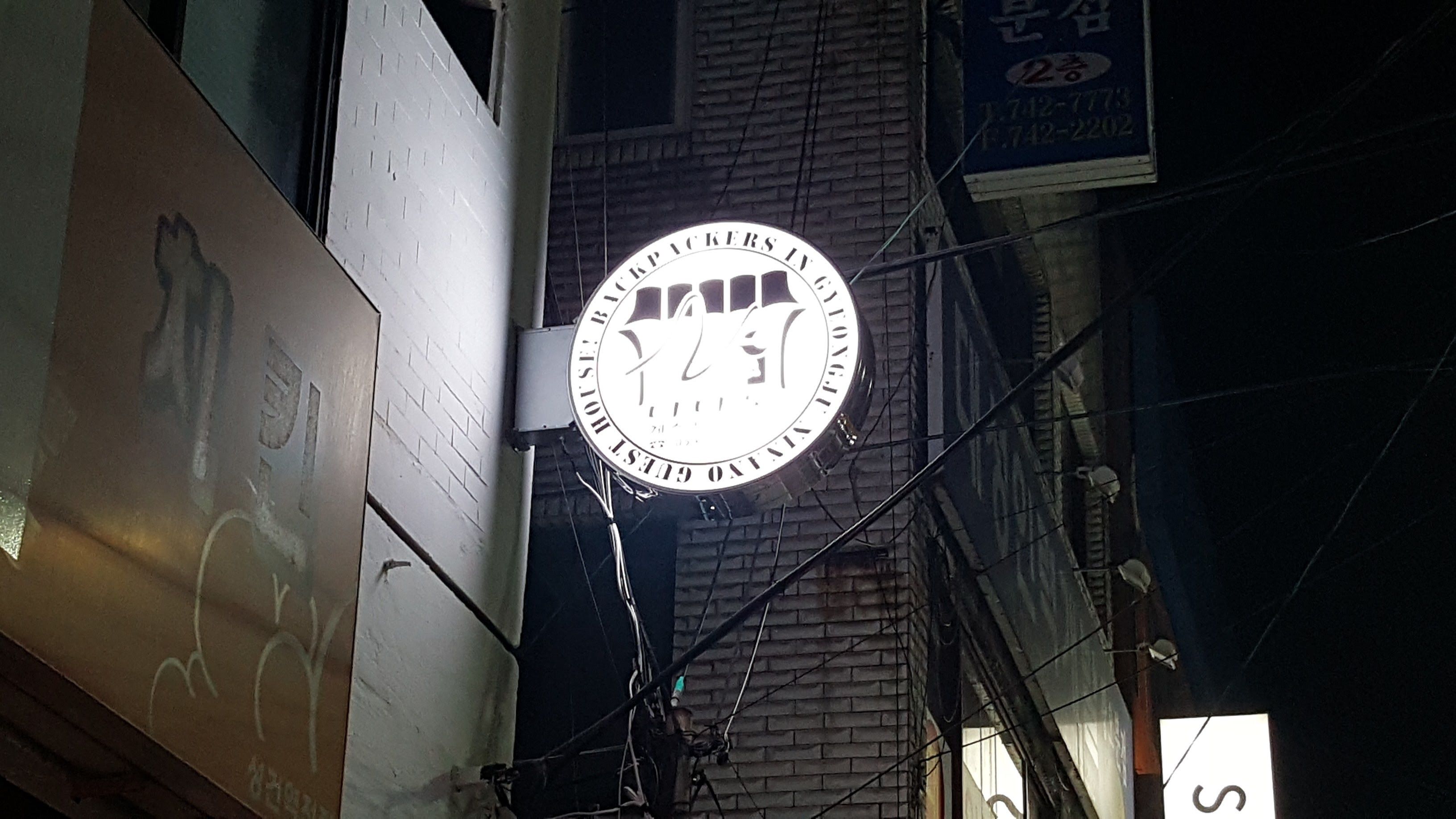 A circular sign with the text "CRACKERS IN GUEST HOUSE" and a phone number.