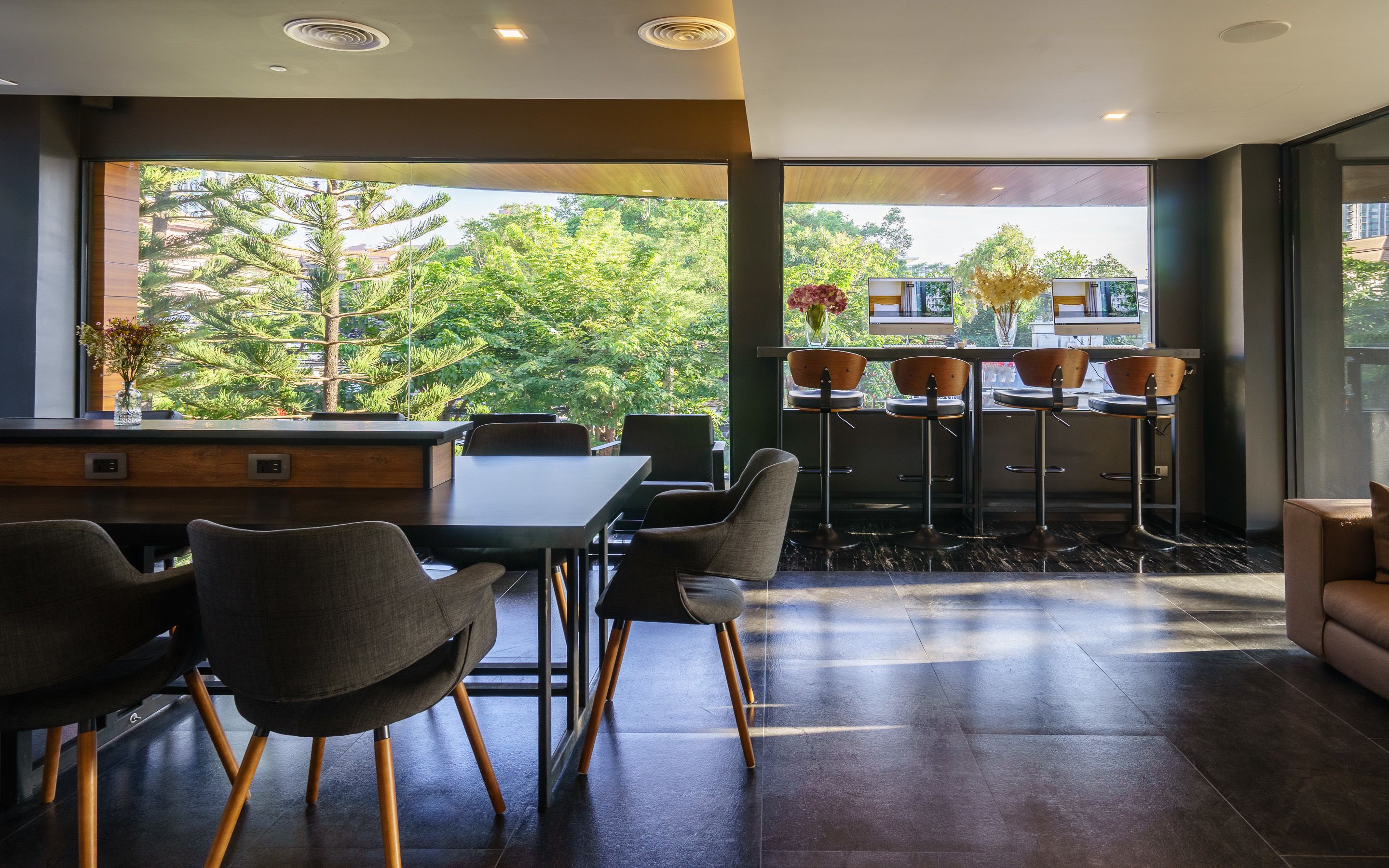 A modern dining area with a large window, a wooden bar, and several bar stools.