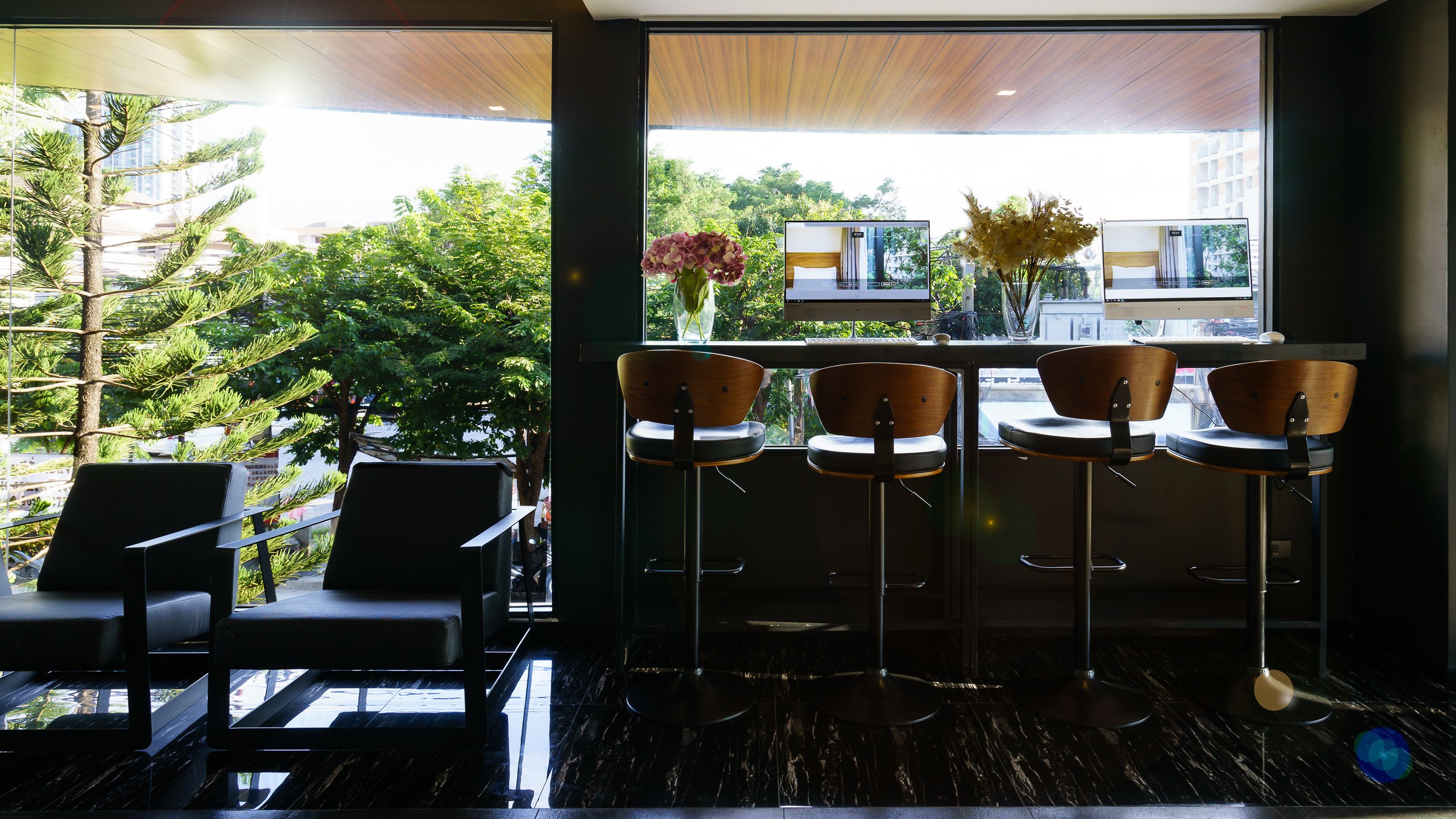 A modern bar area with a view of a cityscape through large windows, featuring a mix of bar stools and high chairs.