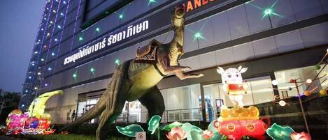Un edificio con un letrero que dice "ANLUM NIGHT D" y una gran escultura iluminada de dinosaurio al frente.