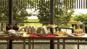 A buffet table with various food items and utensils on a wooden deck with a view of trees and a grassy landscape. - Up-Peak Hotel Simpang Lima Semarang (Semarang)