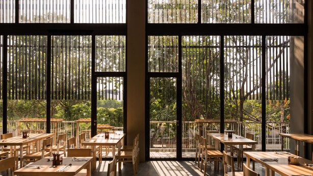 A spacious restaurant with large windows, wooden tables, and chairs. - Up-Peak Hotel Simpang Lima Semarang (Semarang)