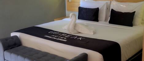 A neatly made bed with a swan-shaped pillow, a black and white bedspread, and a grey upholstered headboard.