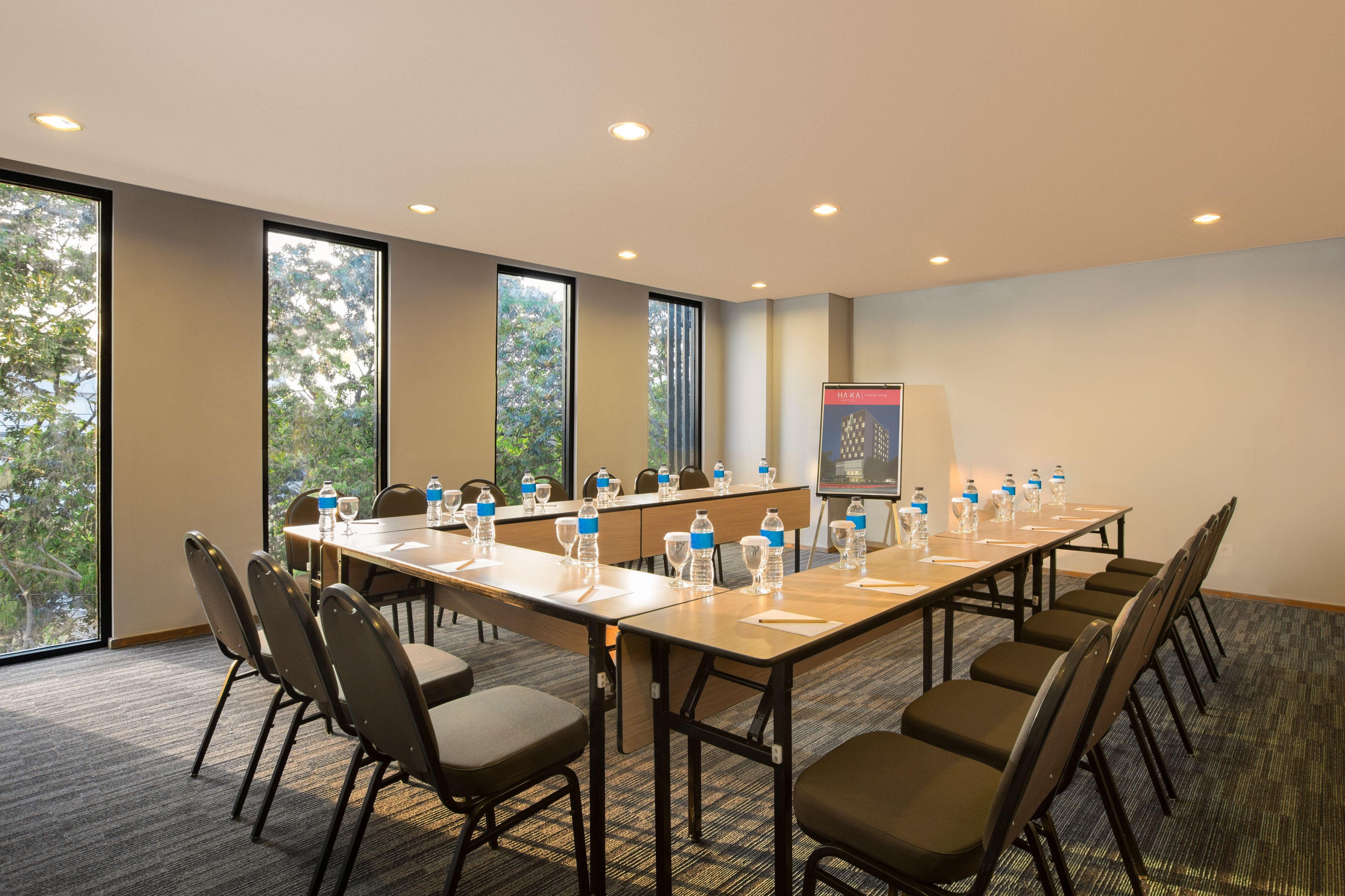 Une salle de conférence avec une longue table, des chaises, des bouteilles d’eau et un écran de présentation.