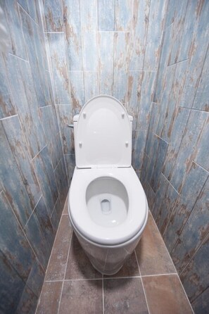 A bathroom with a white toilet, blue and brown tiles on the walls and floor. - BDGR BNB - Hostel (Seogwipo)