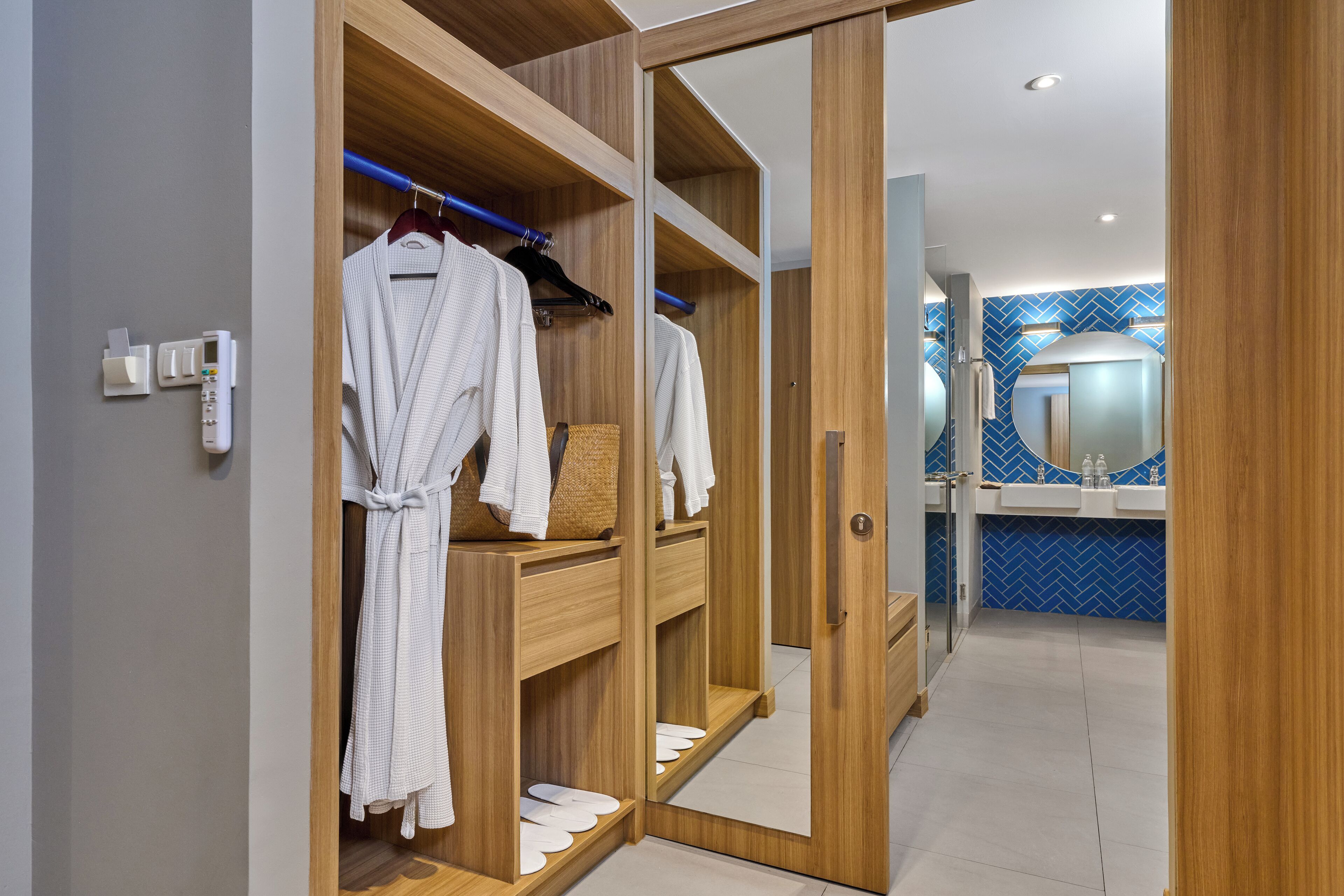A wooden wardrobe with multiple shelves, a mirror, and a hanging rack with robes.
