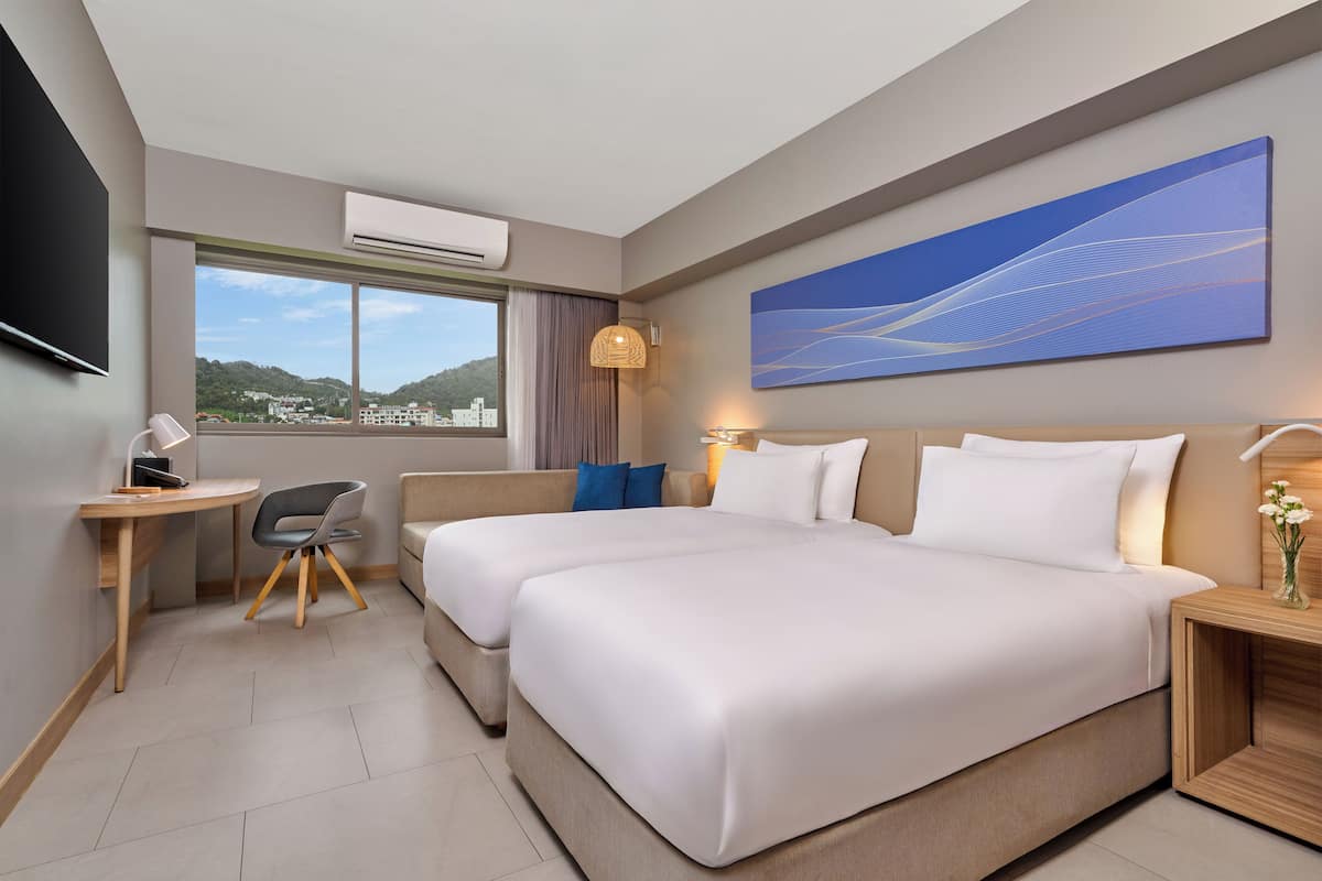 A hotel room with a large bed, a desk, a chair, a TV, and a painting on the wall.