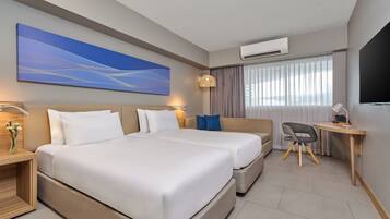 A hotel room with a large bed, a desk, a chair, and a TV.
