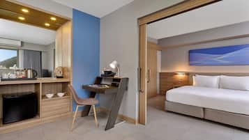 A modern hotel room with a desk, chair, and a bed.
