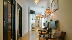 A hallway with wooden flooring, black doors with gold accents, and brown leather chairs.