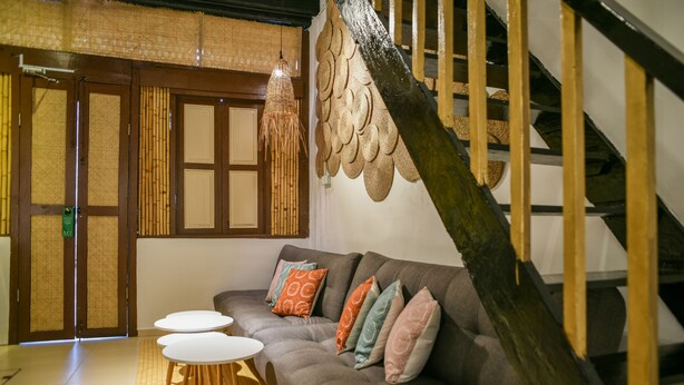 A modern living room with a sofa, a small round table, and a staircase with a wooden railing.