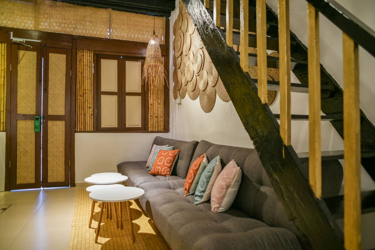 A modern living room with a sofa, a small round table, and a staircase with a wooden railing.