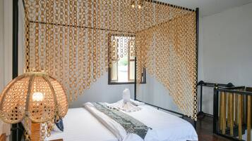A room with a bed, a hanging lamp, and a window with a view.
