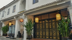 A traditional building with a tiled roof, a large ornate door, and potted plants.