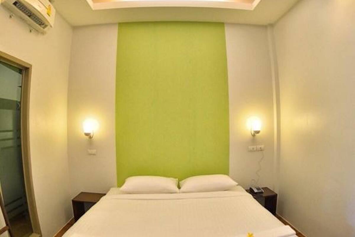 Une chambre d’hôtel avec un grand lit, un mur d’accent de couleur verte et deux lampes de chevet.