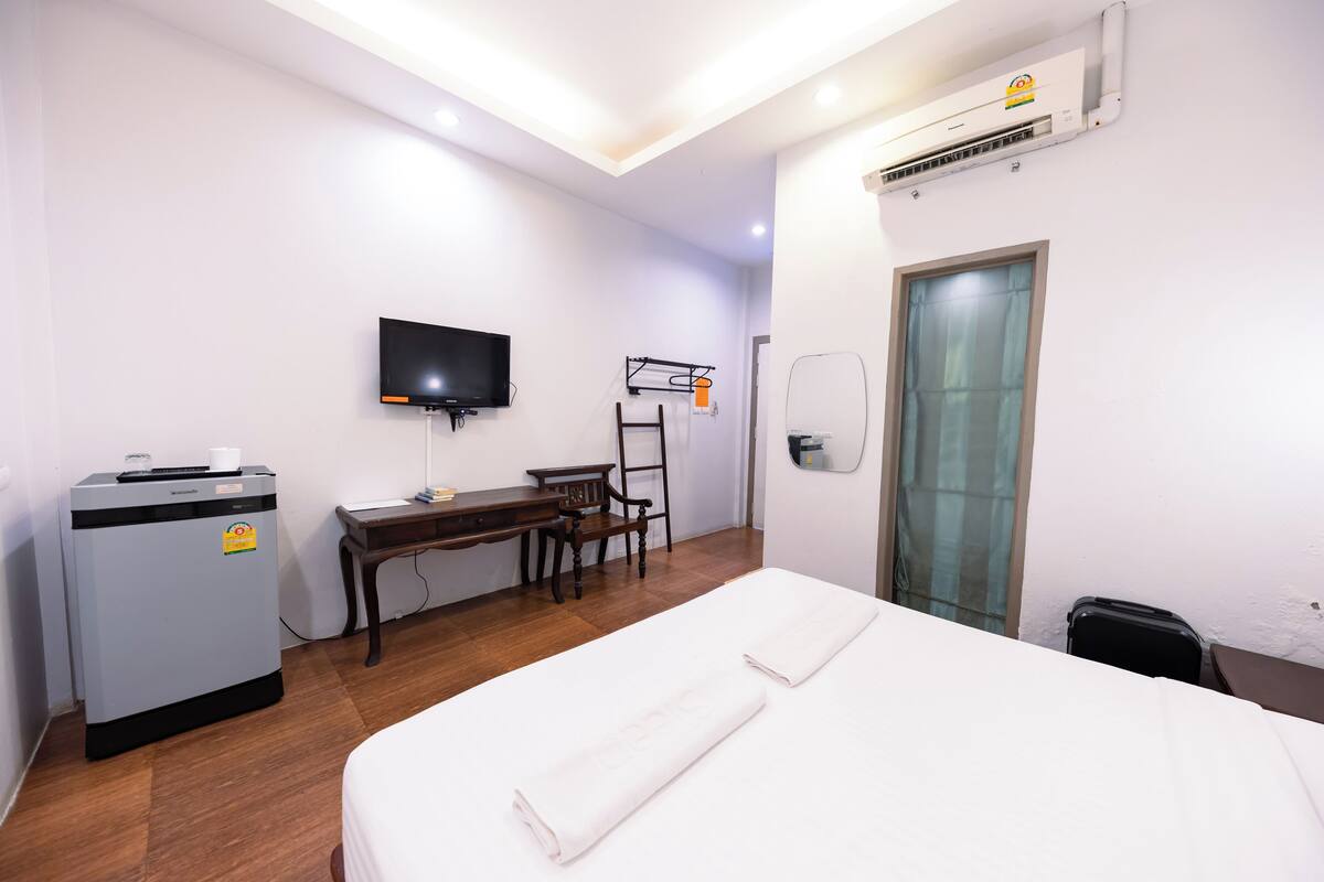 Une chambre d’hôtel équipée d’un lit, d’un bureau, d’une chaise, d’une télévision, d’un climatiseur et d’une fenêtre.
