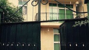 A multi-story building with a balcony, a gated entrance, and a tiled pathway. - Melala Addis Bed & Breakfast (Addis Ababa)