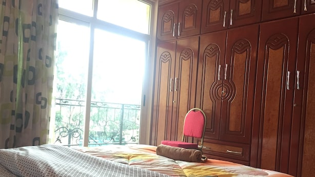 A bedroom with a bed, a chair, and a wardrobe. - Melala Addis Bed & Breakfast (Addis Ababa)