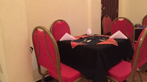 A dining table with a black tablecloth, surrounded by four red upholstered chairs with gold frames. - Melala Addis Bed & Breakfast (Addis Ababa)