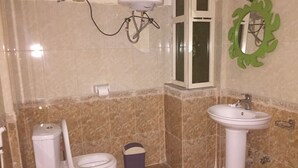 A bathroom with a toilet, bidet, sink, and a green decorative mirror. - Melala Addis Bed & Breakfast (Addis Ababa)