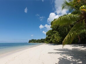 Une plage de sable blanc bordée d’une eau d’un bleu limpide.