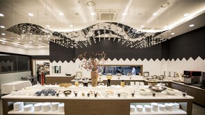 A buffet setup with multiple serving stations, a central decorative tree, and a modern ceiling design. - CS Premier Hotel Seoul (Seoul)