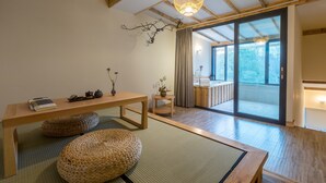 A traditional Japanese-style room with tatami flooring, a low wooden table, and a sliding glass door leading to a balcony. - Sukham Advesa Emei (Leshan)