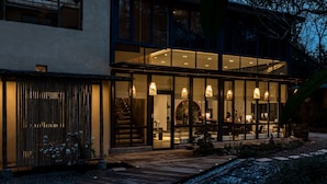 A modern house with a large glass window area, a wooden deck, and a stone pathway. - Sukham Advesa Emei (Leshan)