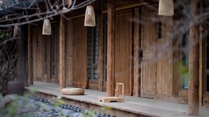 A wooden building with a porch, hanging lamps, and a woven basket. - Sukham Advesa Emei (Leshan)