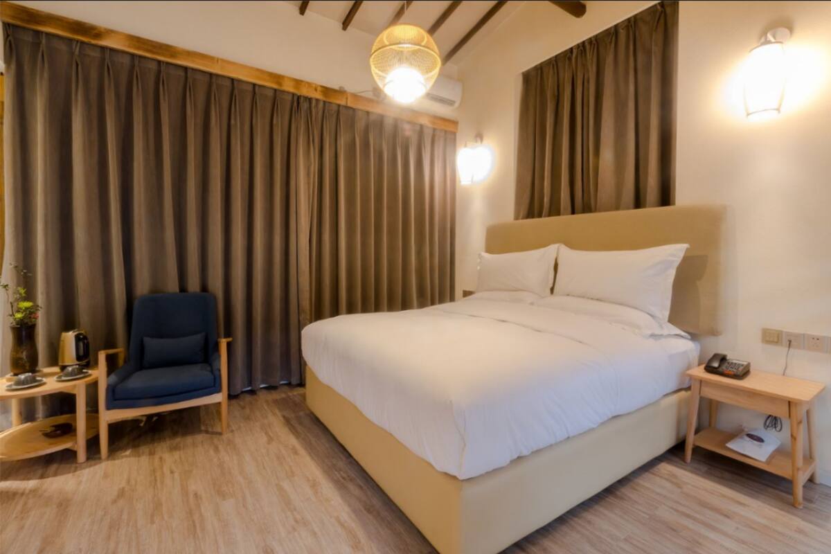 Habitación de hotel con una cama grande, una silla, una mesita de noche y una lámpara.