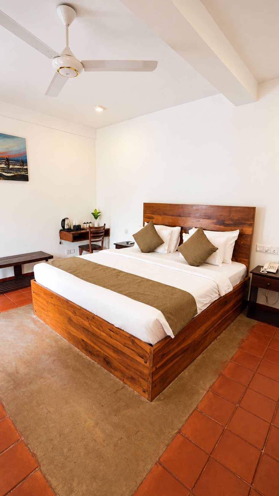 A bedroom with a wooden bed, a ceiling fan, a desk with a chair, and a small table with a plant.