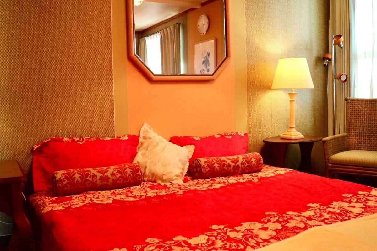 A hotel room with a large bed, two bedside lamps, a chair, and a mirror on the wall.