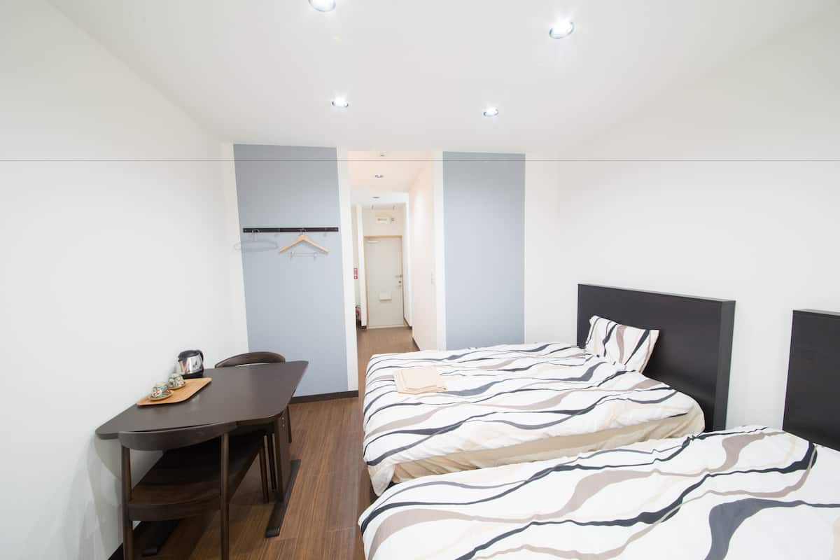 A modern hotel room with a bed, a desk, and a chair.