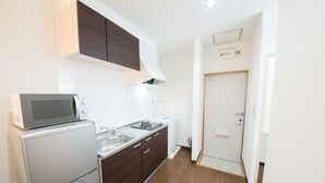 A compact kitchen with a microwave, refrigerator, and wooden cabinets. - Maruka Ishigakijima (Ishigaki)
