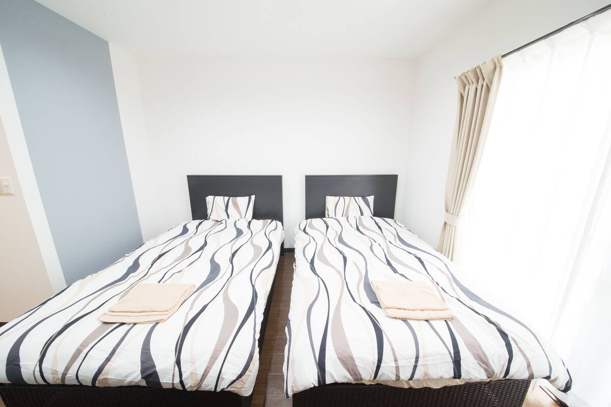 A hotel room with two single beds, each with striped bedding and a headboard.