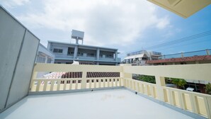 A rooftop terrace with a view of a multi-story building, railings, and a clear sky. - Maruka Ishigakijima (Ishigaki)