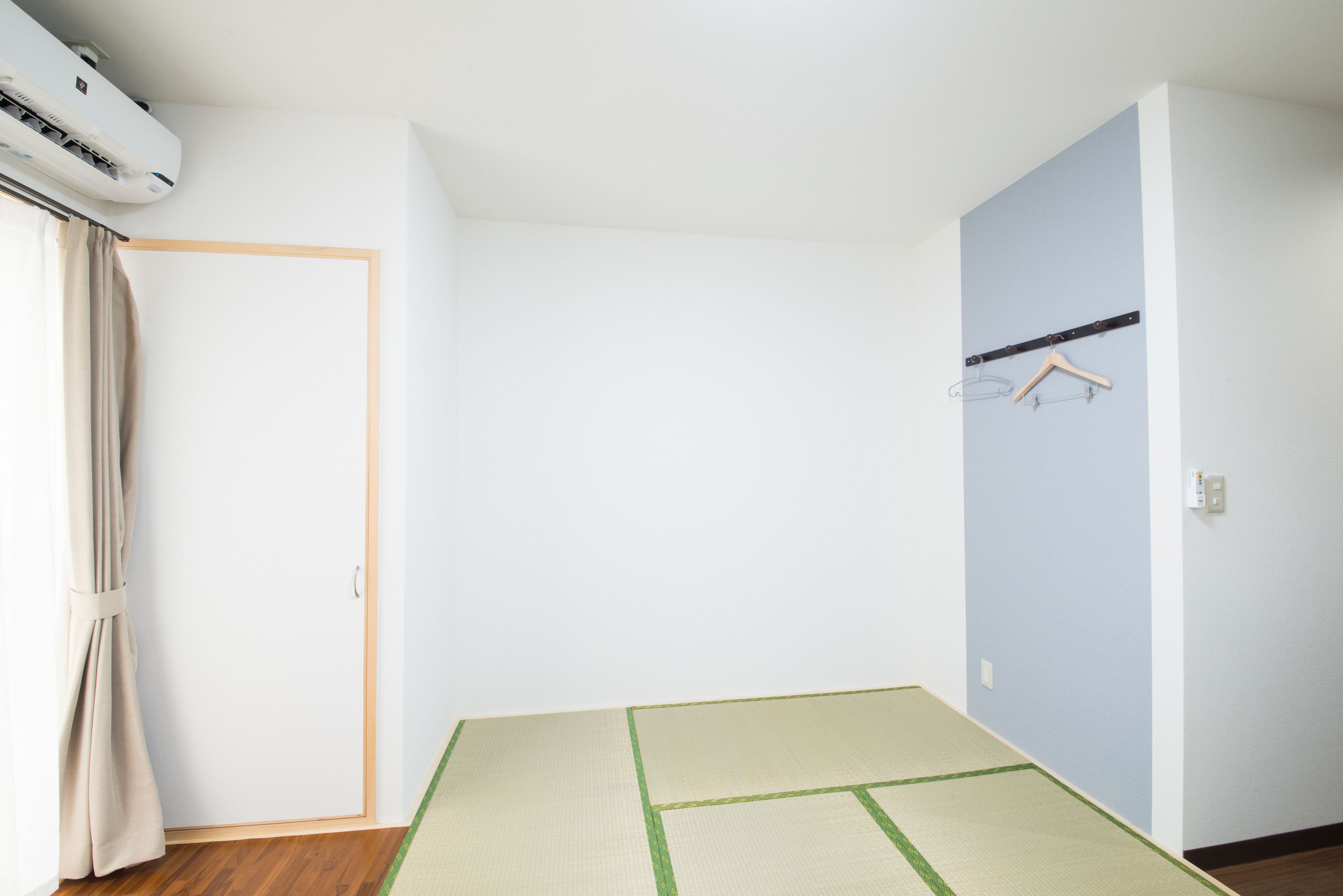 Una habitación con suelo de tatami, una puerta corredera y un aire acondicionado de pared.