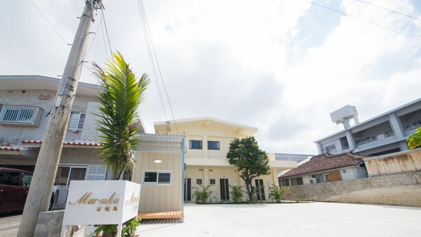 A hotel with a signboard, a palm tree, and a building with a tiled roof. - Maruka Ishigakijima (Ishigaki)