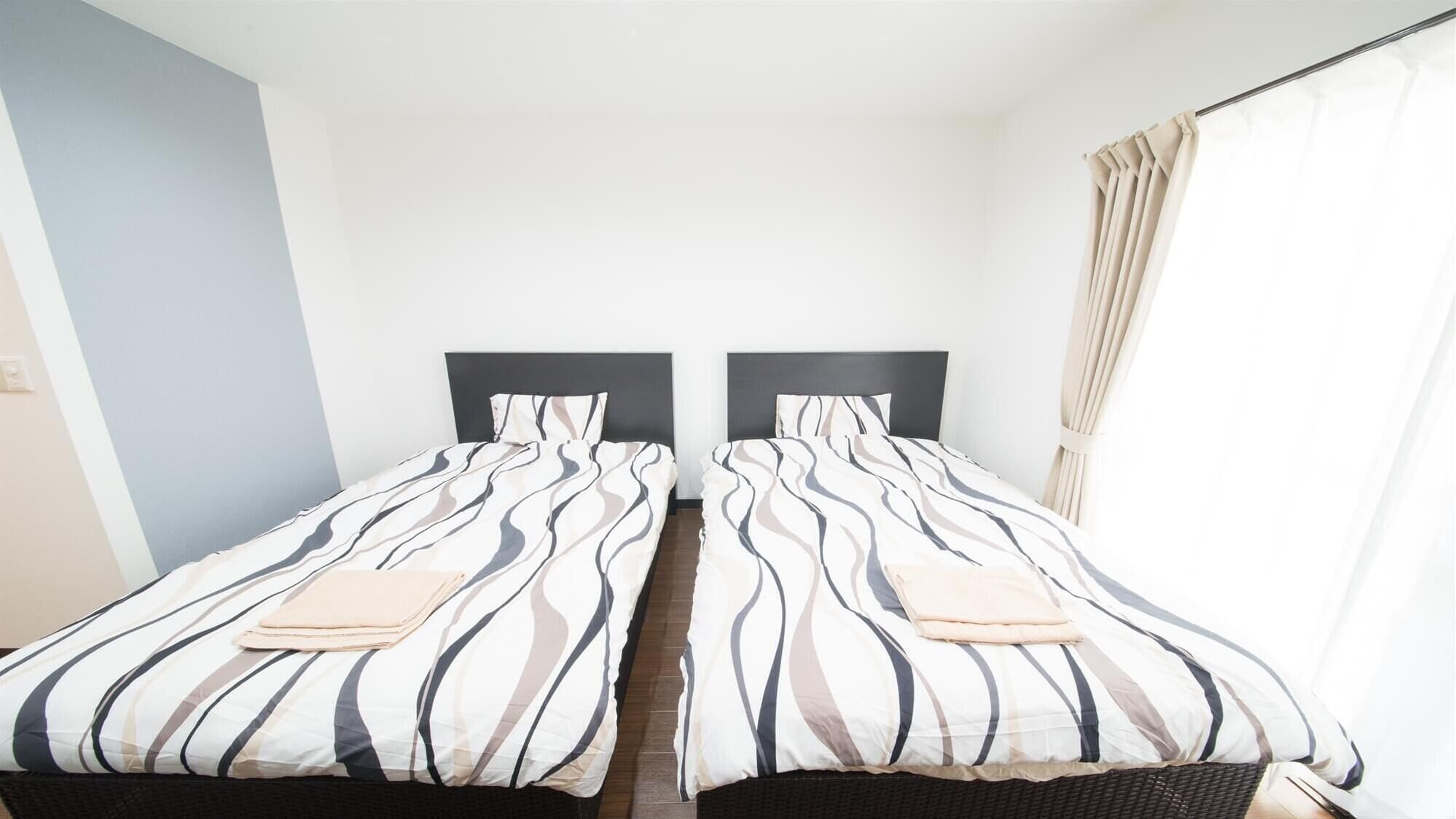 Habitación doble con dos camas, cada una con ropa de cama a rayas y cabeceros.