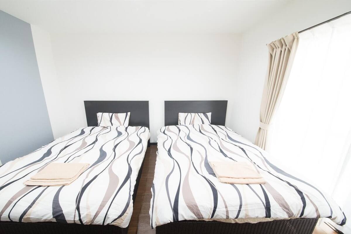 A double room with two beds, each with striped bedding and headboards.