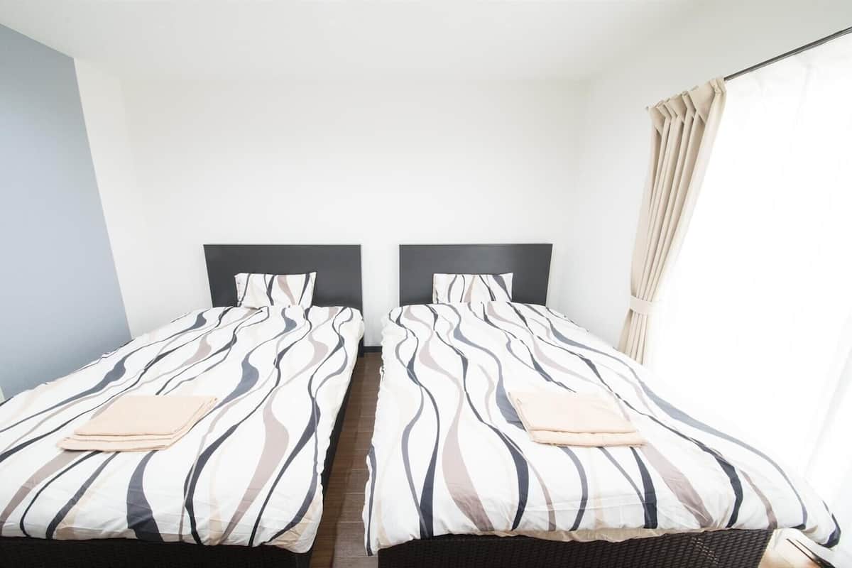 A twin room with two beds, each with striped bedding, a dark headboard, and a window with curtains.