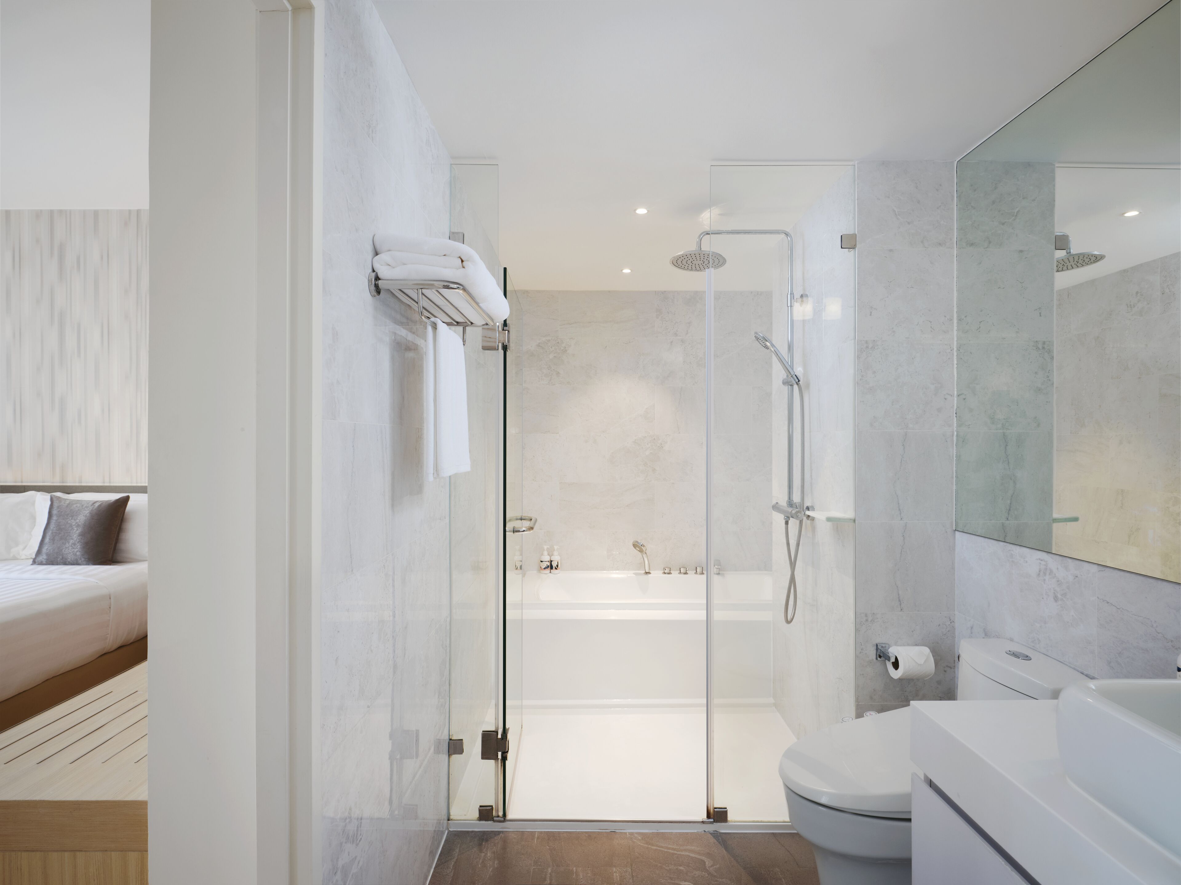 Een moderne badkamer met een douchecabine van glas, een witte badkuip en een toilet.