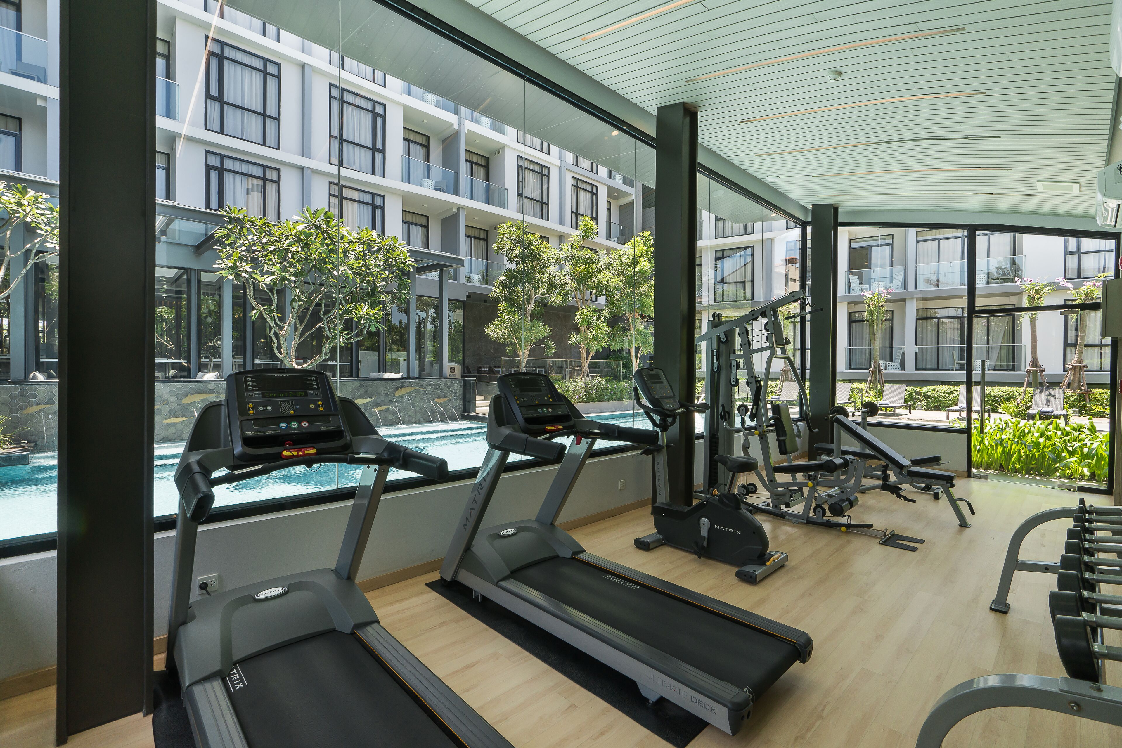 Un gimnasio moderno con cintas de correr, máquinas de pesas y vistas a la piscina.