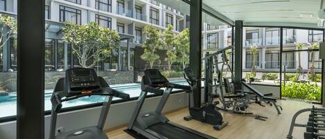 Un gimnasio moderno con cintas de correr, máquinas de pesas y vistas a la piscina.