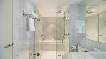 A modern bathroom with a glass-enclosed shower, a separate bathtub, and a vanity with a large mirror.