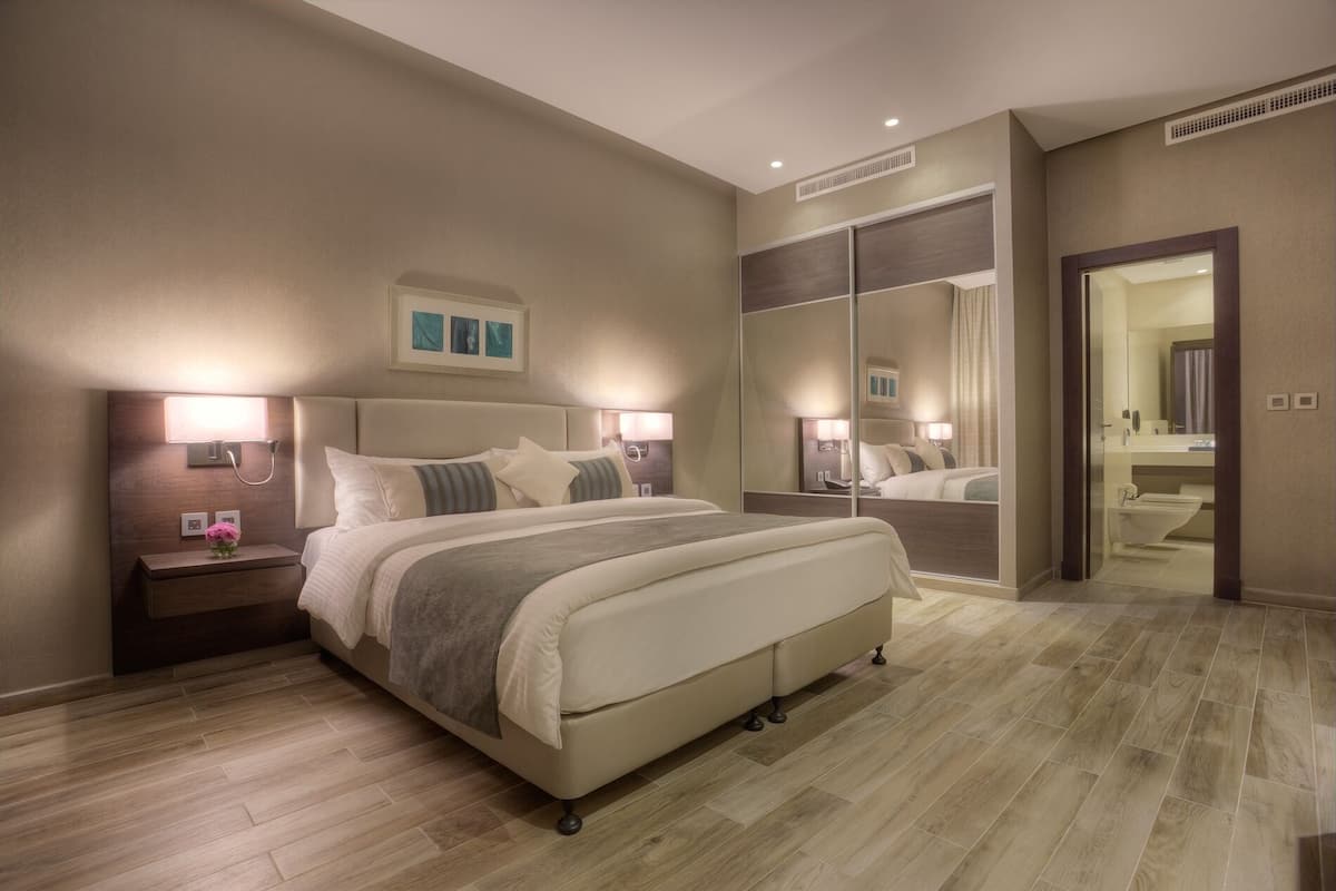 Un dormitorio de hotel moderno con una cama grande, lámparas de noche, una mesita de noche y un espejo.