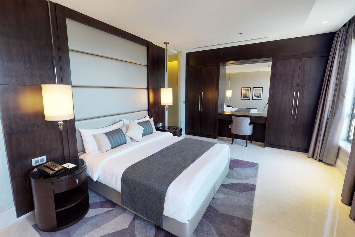 Una habitación de hotel moderna con una cama grande, mesitas de noche, un escritorio y un armario.